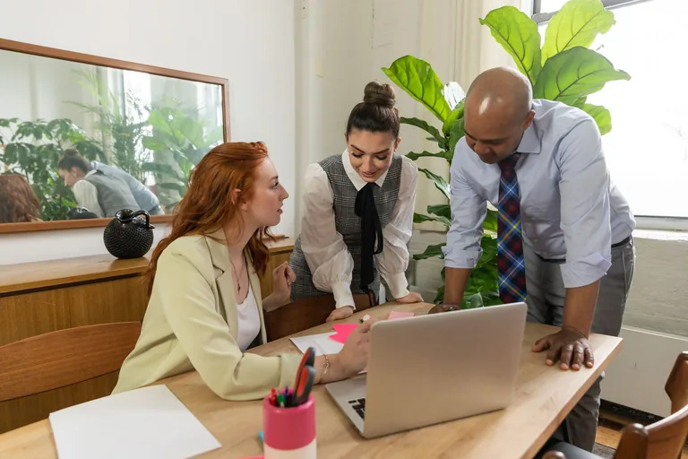 Colleagues reviewing work together around a laptop